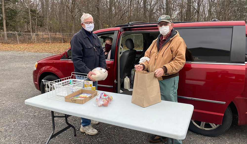Town of Montgomery Food Pantry Treasurer Peter Sullivan (left) and volunteer Clifford Medley (right) give Bea Conn (center) a Thanksgiving meal.